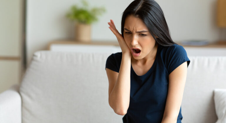 Girl Suffering From Tooth Pain Touching Cheek Sitting At Home